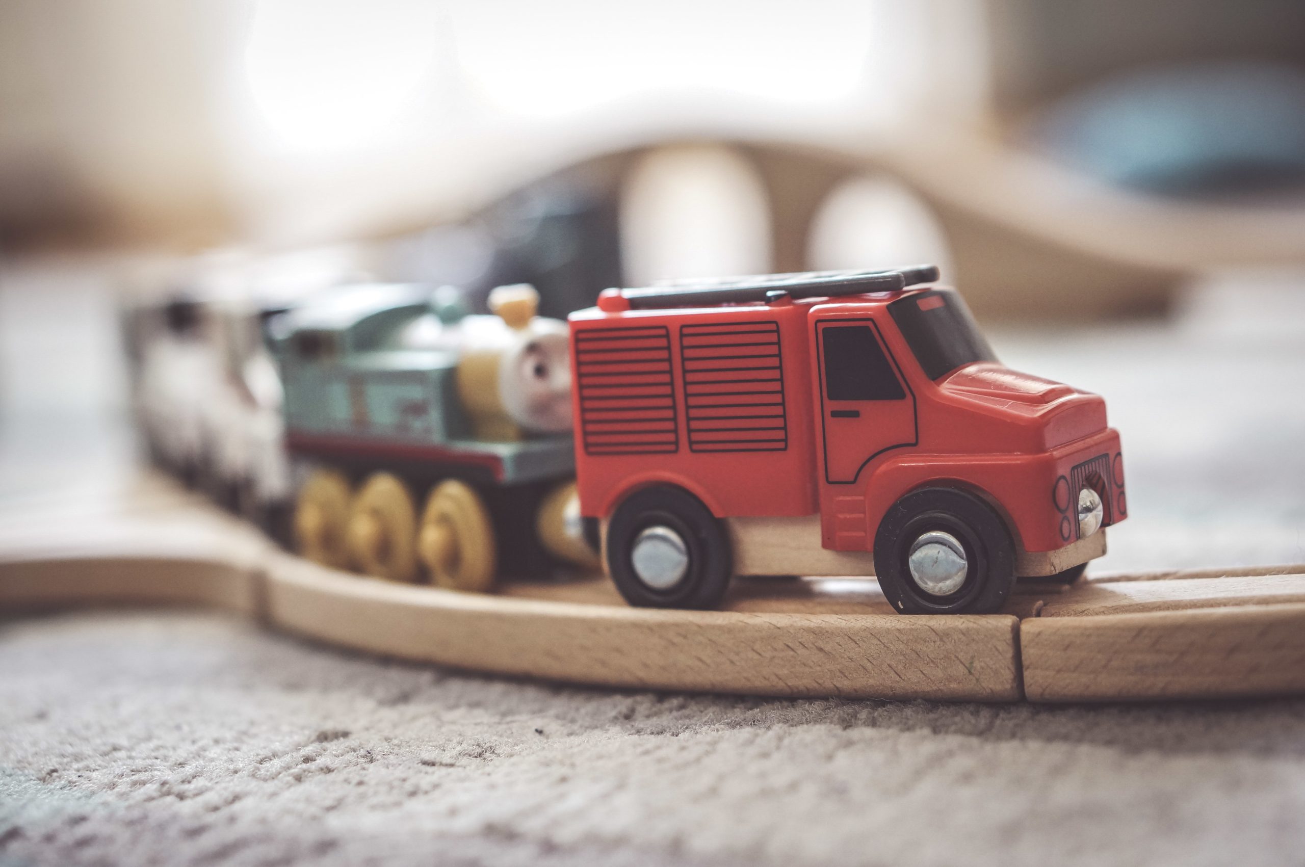 A closeup shot of a small toy car on a wooden train track